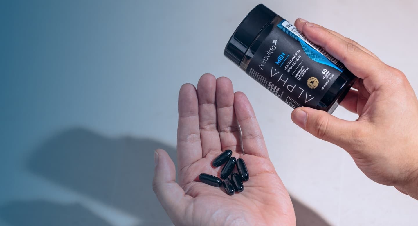 Alpha Men - cápsulas softgel Mão segurando o frasco de Alpha Men com as cápsulas softgel