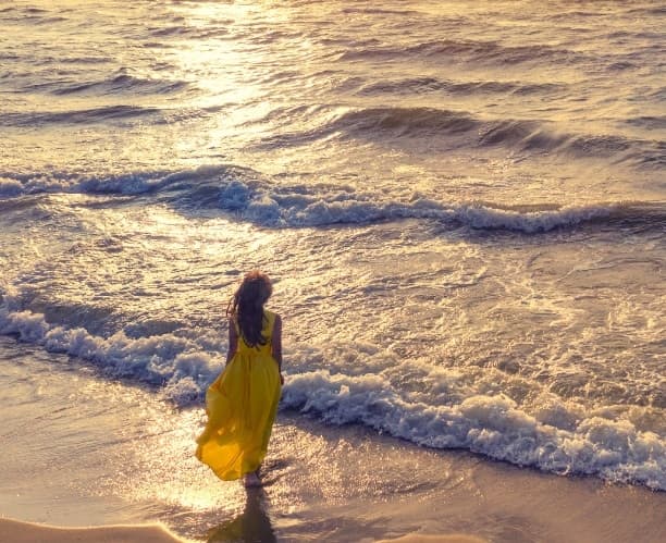 Mulher caminhando na praia ao pôr do sol Mulher caminhando na praia ao pôr do sol